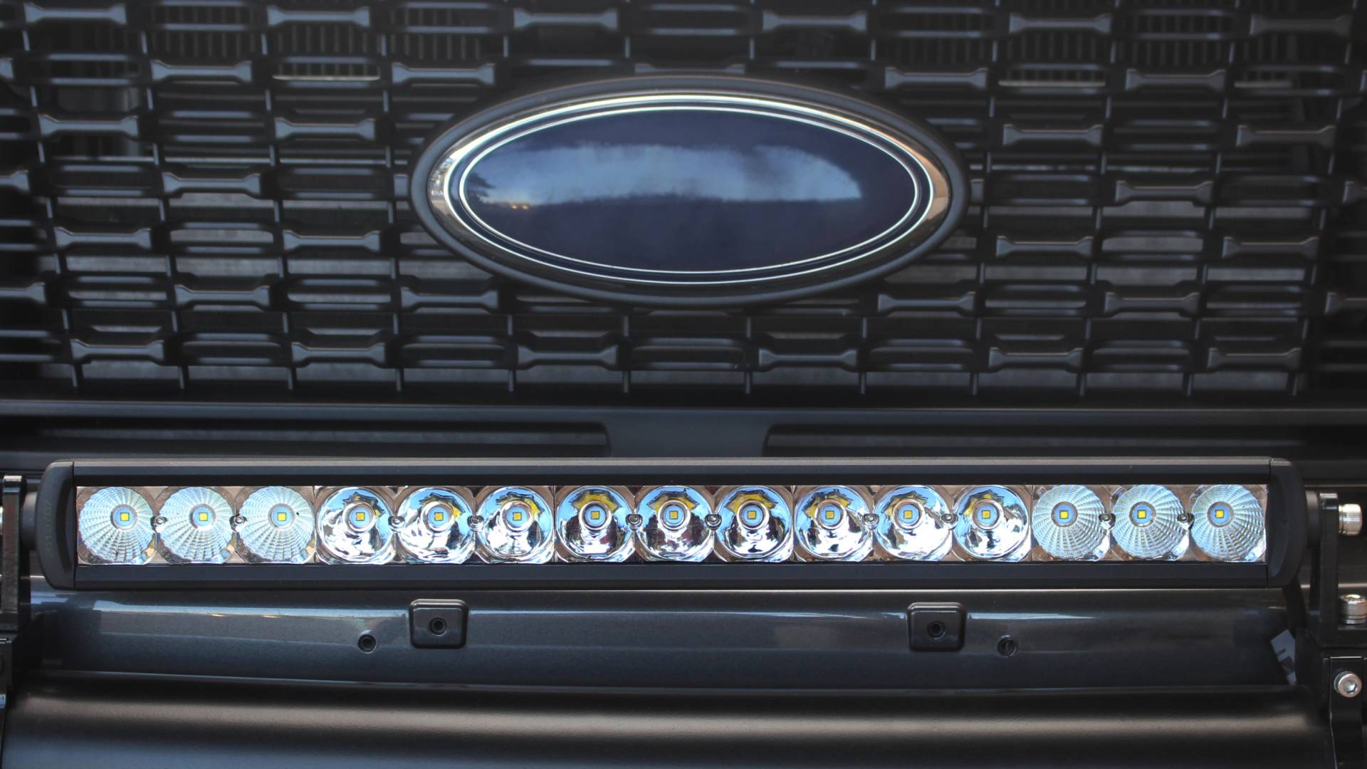A long, slender light bar is installed on the front bumper of a vehicle. The lights are not illuminated.