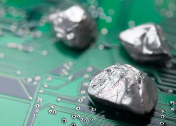 Little chunks of metal sitting on top of a green electronic circuit board. There are three pieces of this metal.