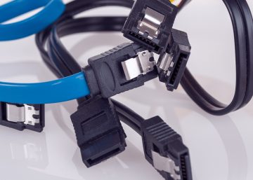 Three different SATA cables sit tangled on a white background. One is yellow, one is blue, and one is black.